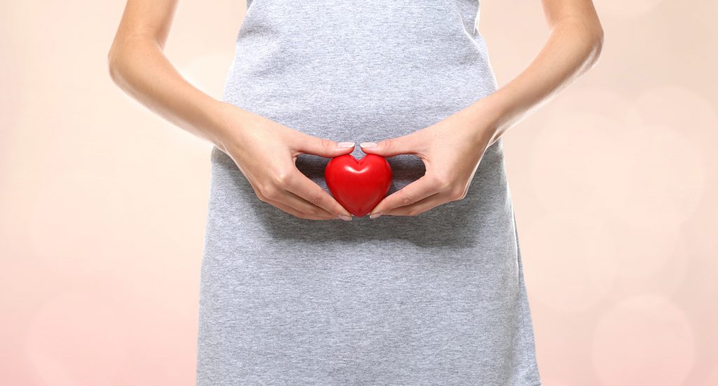 women holding a red heart in front of her hips